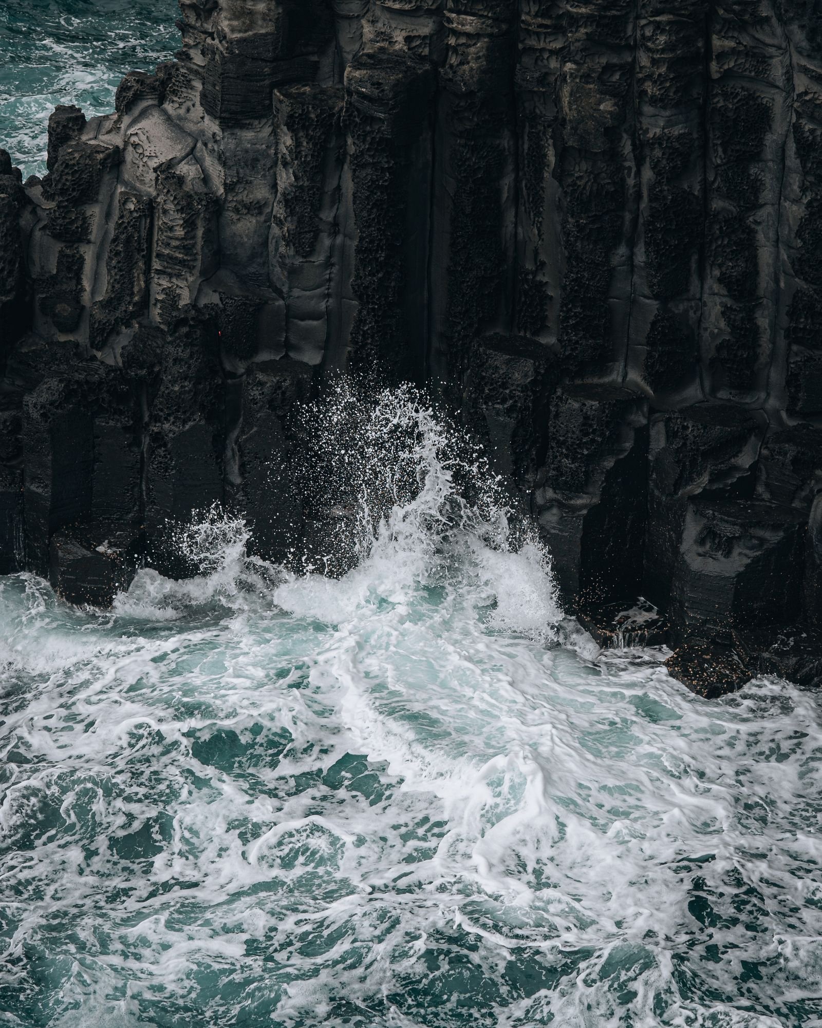 Waves against volcanic coastal cliffs on Jeju Island, South Korea