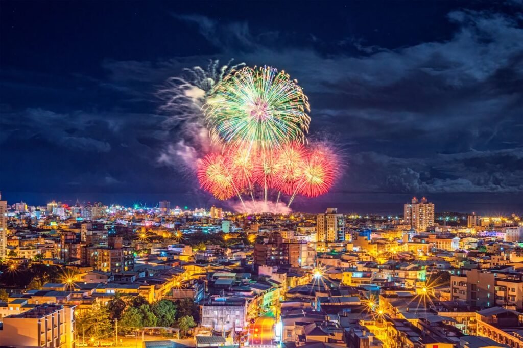 Colorful fireworks illuminate the night sky over a bustling Taiwan city, creating a festive and lively atmosphere.