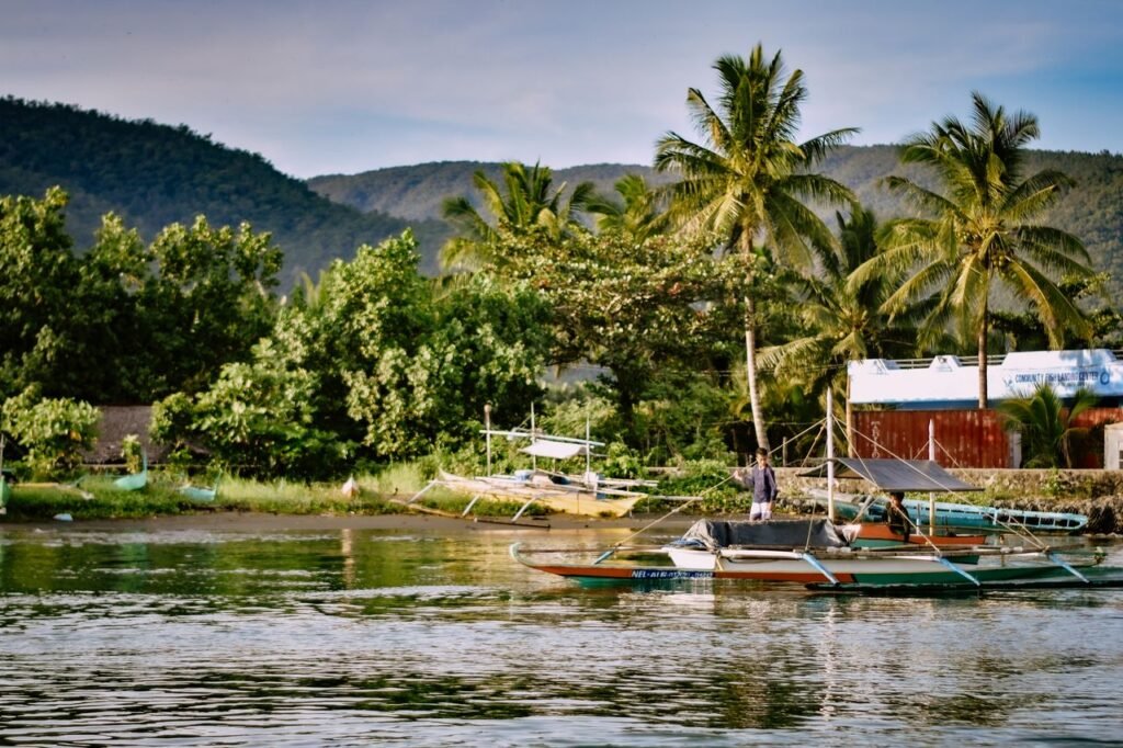 Scenic view of tropical harbor with traditional boats and lush greenery under a clear sky.